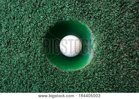 Mini golf scene with ball and hole. Can be used like background. Sunny day at resort park