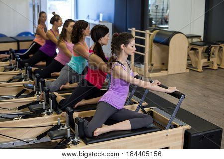 Group of women exercising on reformer in gym