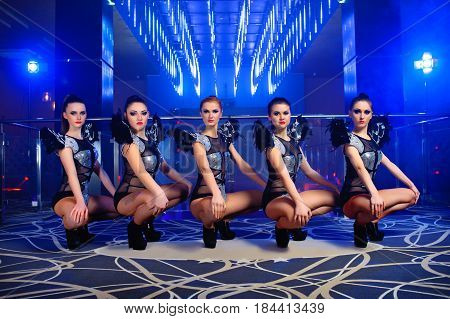 Horizontal shot of five beautiful exotic dancers in similar outfits performing together at the disco club profession occupation job dancing performing entertaining leisure luxury enjoyment.