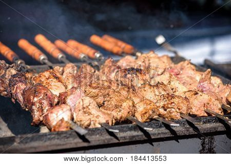 closeup of some meat skewers being grilled in a barbecue.