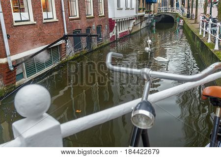 Water canal and city street with bicycle parking lot in Dutch Delft old city