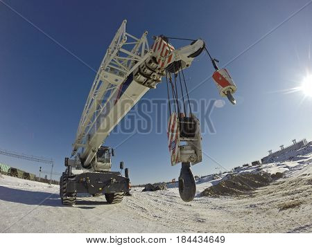 Mobile crane in work at a construction site winter. Crane on rubber wheels with raised boom