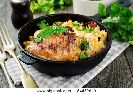 Rice with corn soy sauce and fried chicken thigh on a cast-iron frying pan. Selective focus.