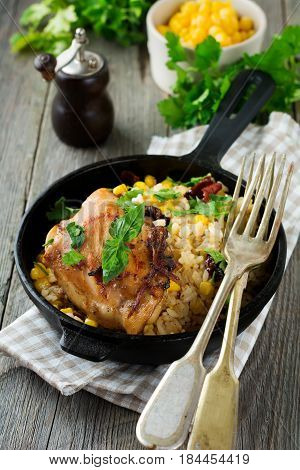 Rice with corn soy sauce and fried chicken thigh on a cast-iron frying pan. Selective focus.