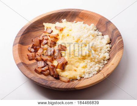 Polenta with bacon and salted cheese on the wooden table - traditional Carpathian dish