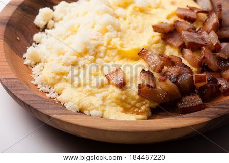 Polenta with bacon and salted cheese on the wooden table - traditional Carpathian dish