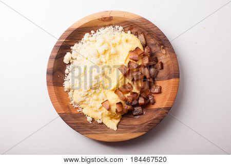 Polenta with bacon and salted cheese on the wooden table - traditional Carpathian dish, top view