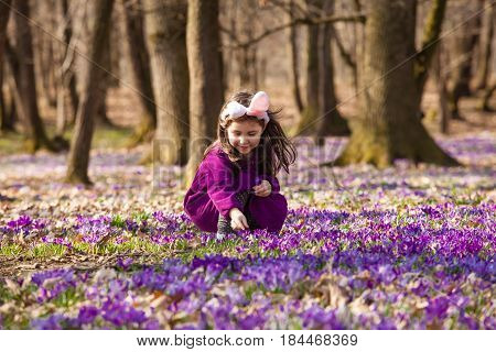 Little girl with banny ears peeping from behind a tree in the park