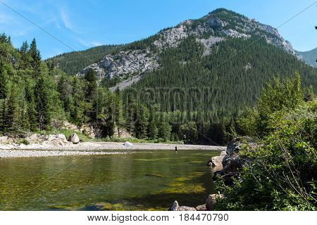Iew Of A Lake With Trees And Mountains In The Distance.
