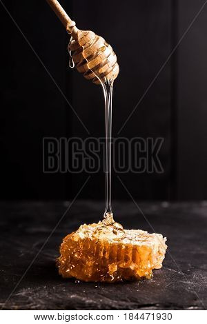Honey drip and comb over black slate background