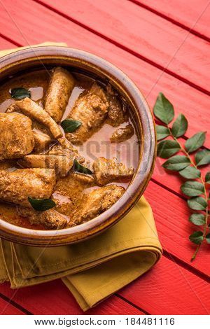 tasty fish curry served with white cooked basmati rice with curry leaves in the background, favourite coastal indian food