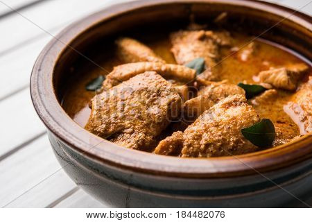 tasty fish curry served with white cooked basmati rice with curry leaves in the background, favourite coastal indian food