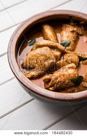 tasty fish curry served with white cooked basmati rice with curry leaves in the background, favourite coastal indian food