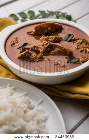 tasty fish curry served with white cooked basmati rice with curry leaves in the background, favourite coastal indian food
