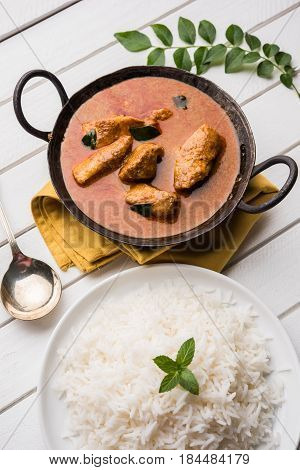 tasty fish curry served with white cooked basmati rice with curry leaves in the background, favourite coastal indian food