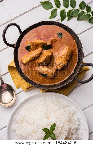 tasty fish curry served with white cooked basmati rice with curry leaves in the background, favourite coastal indian food