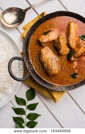 tasty fish curry served with white cooked basmati rice with curry leaves in the background, favourite coastal indian food