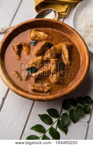 tasty fish curry served with white cooked basmati rice with curry leaves in the background, favourite coastal indian food