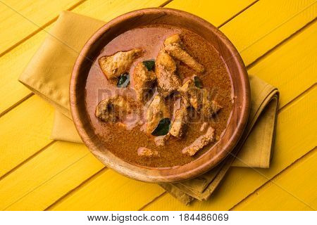 tasty fish curry served with white cooked basmati rice with curry leaves in the background, favourite coastal indian food