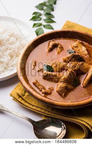 tasty fish curry served with white cooked basmati rice with curry leaves in the background, favourite coastal indian food
