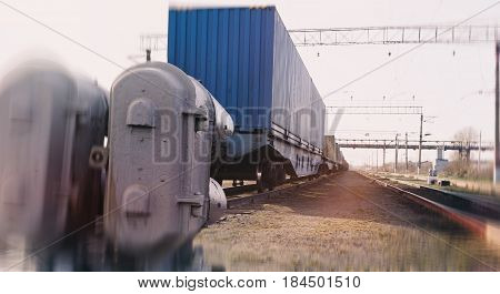 Train container. The container was loaded onto the train platform. The train is on the tracks. In the foreground a semaphore for rail. Stylized blur photos.