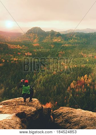 Hiker With Camera On Tripod Takes Picture From Rocky Summit. Alone Photographer At Edge Photograph L