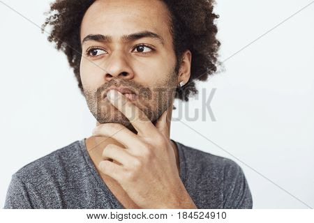 Close up portrait of concentrated serious african male thinking about past and future plans or dreaming where to go eat over white background. Copy space.