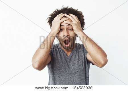 Portrait of surprised and shocked african man with opened mouth finding out he missed a sale or is late to work or forgot to pick up his kids from school over white background. Copy space.
