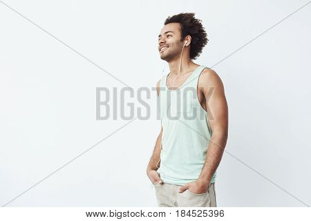 Young african man smiling listening to music in headphones over white background. Copy space.