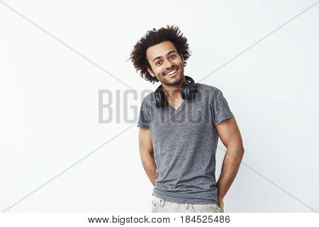 Happy african man with headphones smiling looking at camera over white background. Copy space.