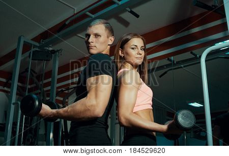 Man and woman with dumbbells in the gym.