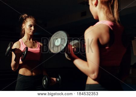 Young girl doing exercise for biceps with dumbbells