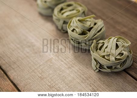 Tagliatelle pasta arranged in a row on wooden background