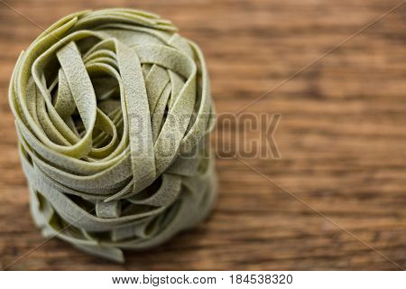 Roll of tagliatelle pasta on wooden surface