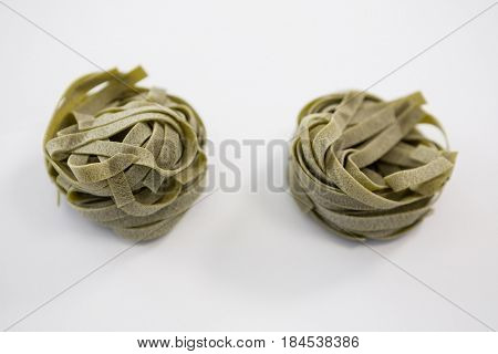 Roll of tagliatelle pasta on white background