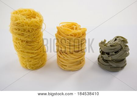 Various pasta arranged in a row on white background