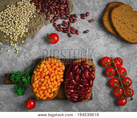 Braised beans in tomato sauce on vegetarian sandwiches with bean. Open sandwiches with bread stewed white and red beans. Raw beans pieces of rye bread for sandwiches. Top view.