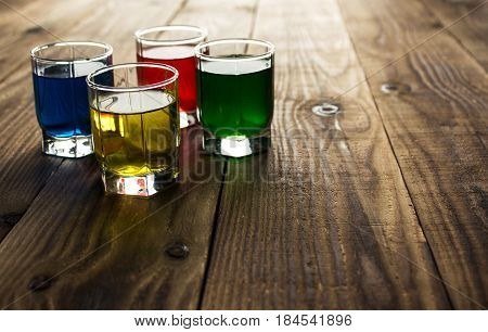 blue yellow green red alcohol shot drinks on wooden background