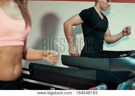 Man and woman running on a treadmill in the gym. Close up.