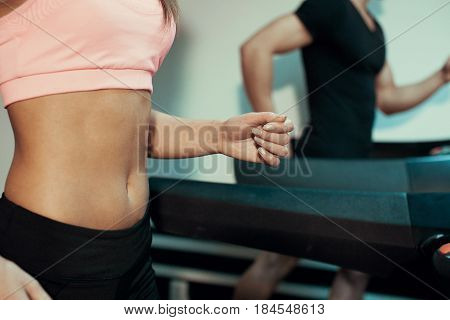 Man and woman close up running on a treadmill in the gym
