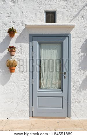 Wooden door with flowerpots. Locorotondo. Puglia. Italy.
