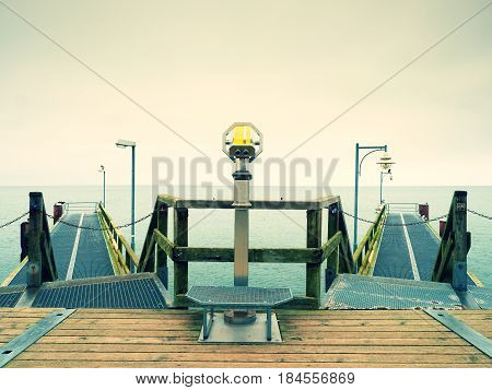 Long touristic mole within autumn misty morning. Wet and slippery wooden floor constrution above smooth sea.