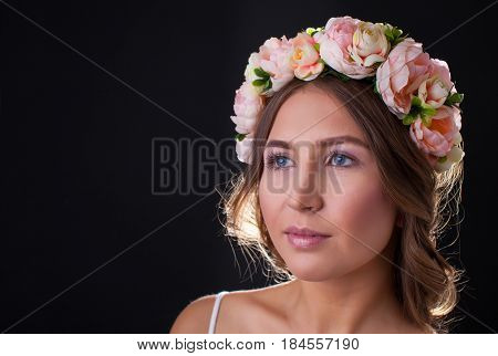 Beautiful girl in wreath of flowers closeup
