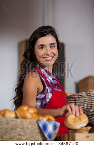 Female staff holding basket of sweet foods in bakery section of supermarket