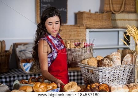 Female staff holding basket of sweet foods in bakery section of supermarket