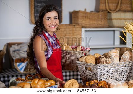 Female staff holding basket of sweet foods in bakery section of supermarket
