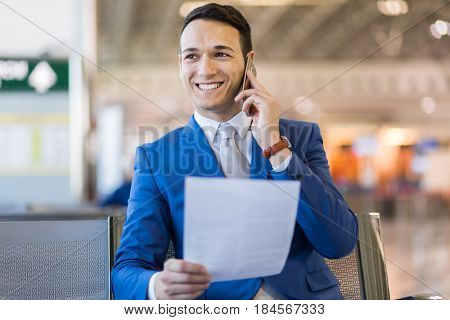 happy businessman talking on cell phone at airport