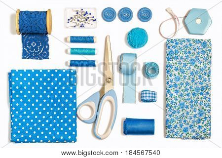 Sewing kit accessories and equipment for sewing blue shades. Various sewing accessories and tools for needlework: fabric threads scissors buttons needles braid ribbons. Flat lay top view