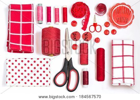 Sewing kit accessories and equipment for sewing red shades. Various sewing accessories and tools for needlework: fabric threads scissors buttons needles braid ribbons. Flat lay top view