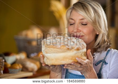Female staff smelling a sweet food in supermarket